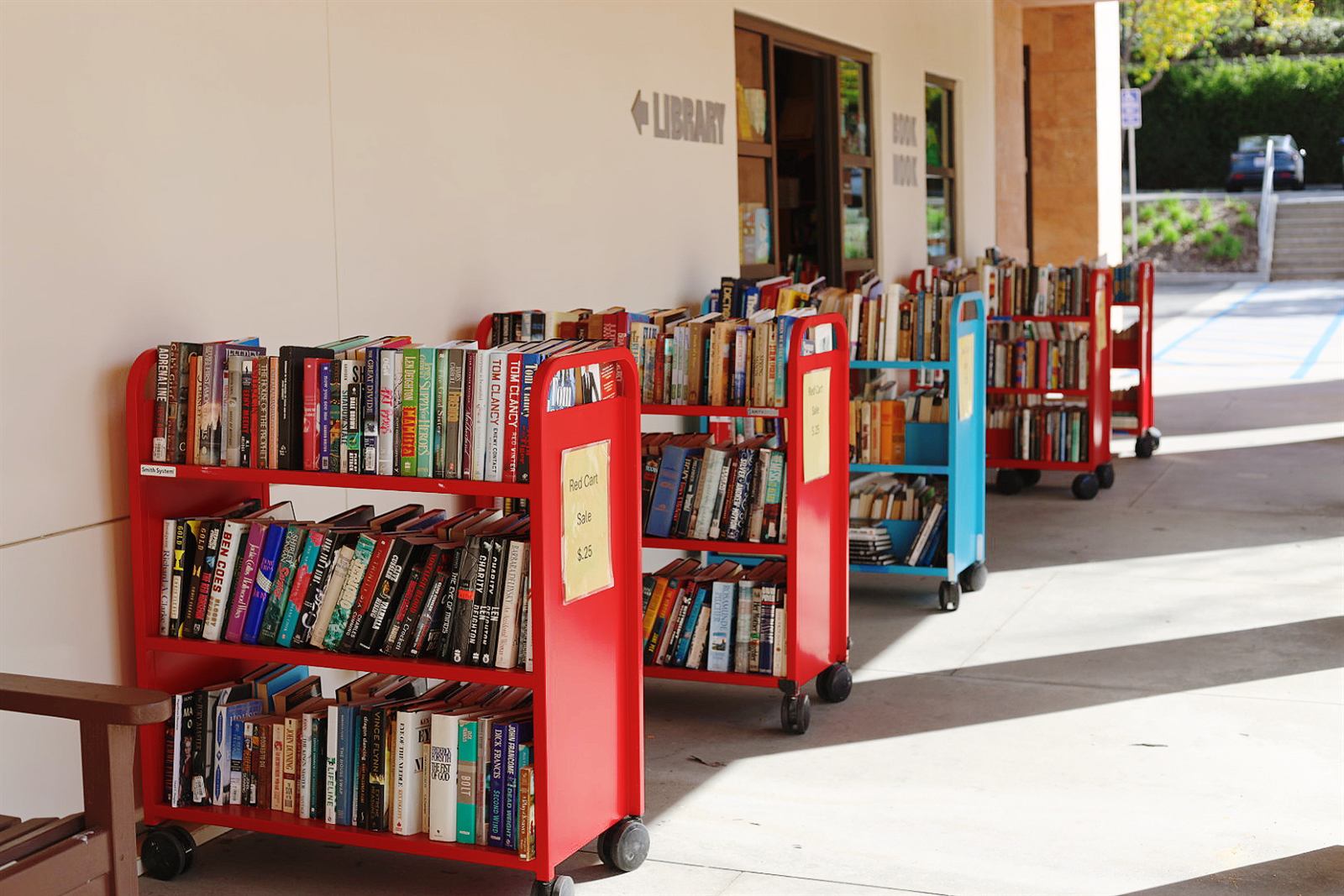 Discount book carts lined up outside the Book Nook, next to the library entrance