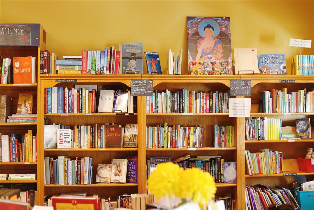 Bookshelves labeled by subject inside the Book Nook, with fresh flowers on the counter